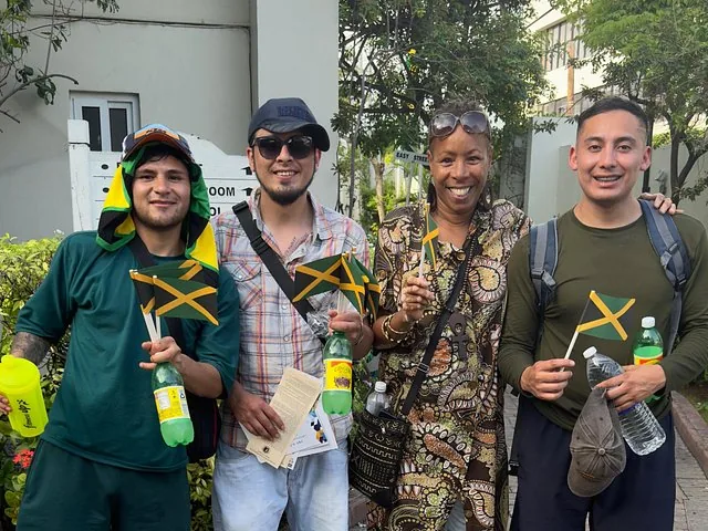 Eine Gruppe von vier Personen hält kleine jamaikanische Flaggen und lächelt für ein Foto.