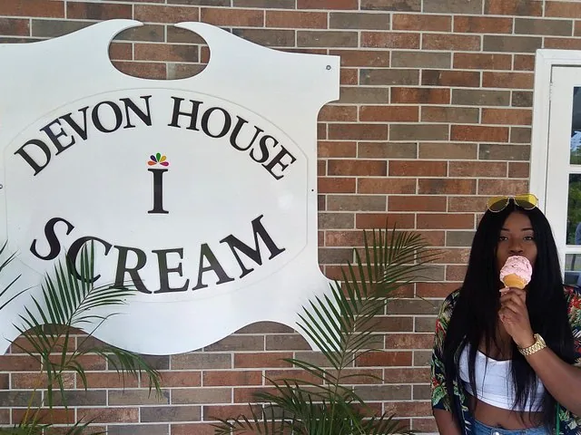 Frau isst Eis vor dem Schild von Devon House I-Scream.