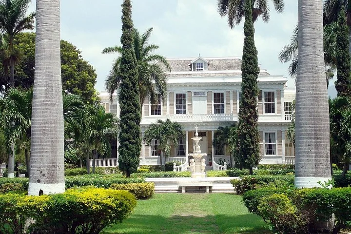 Blick auf das historische Herrenhaus Devon House, umgeben von Palmen und Gärten.